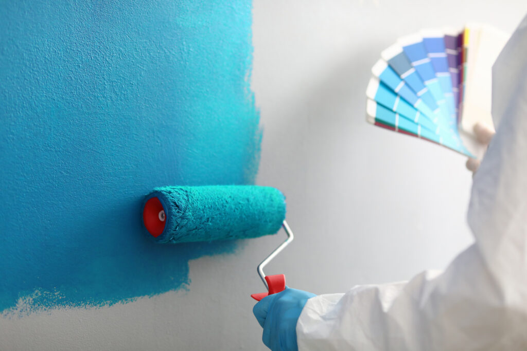 Master painter holds in his hands color palette with shades of blue Homeowner preparing an interior wall for a painting project