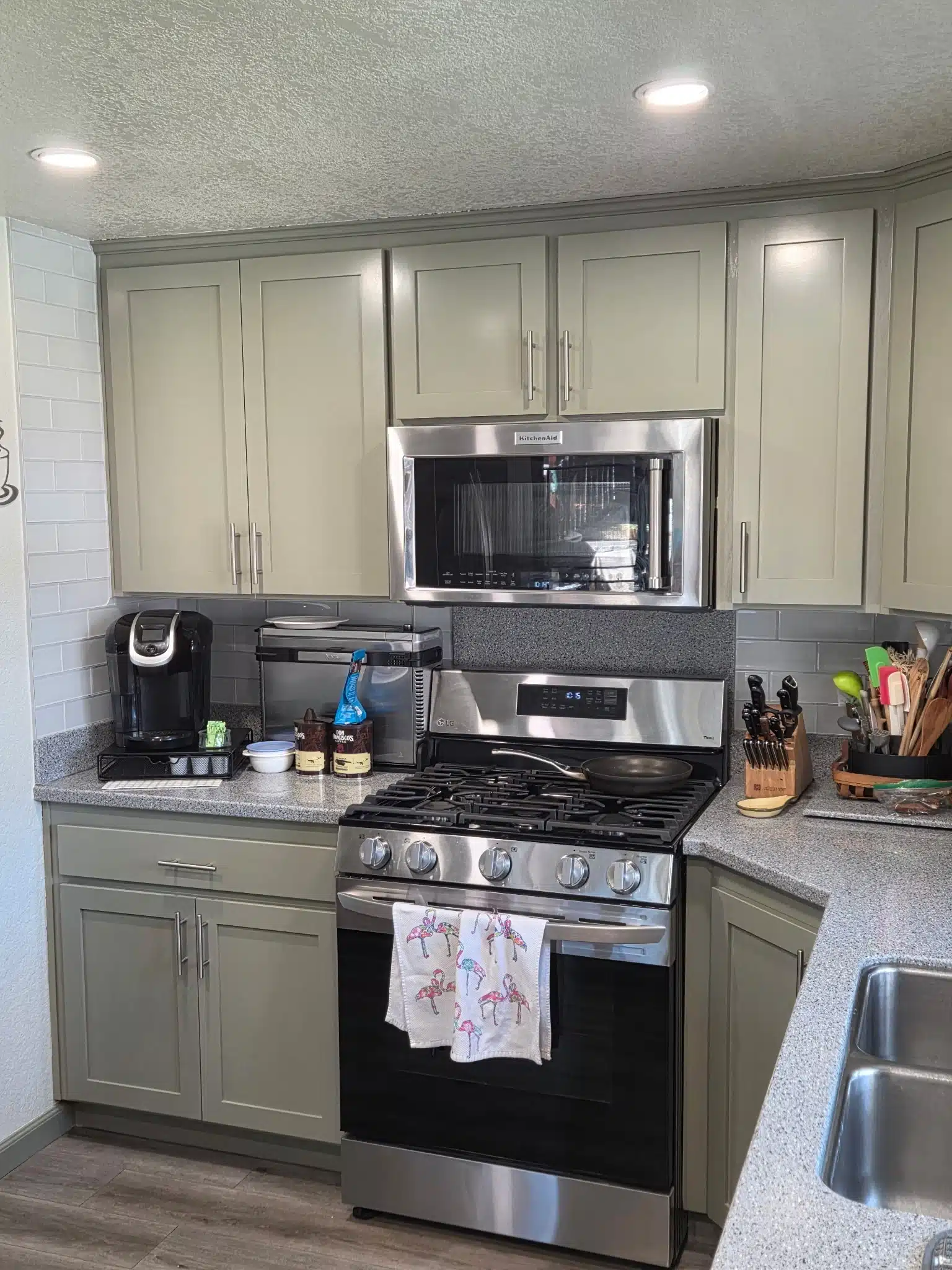 Kitchen Cabinet Painting with Sage Green Cabinets and White Backsplash Modern kitchen featuring newly painted sage green cabinets, stainless steel appliances, and white subway tile backsplash.
