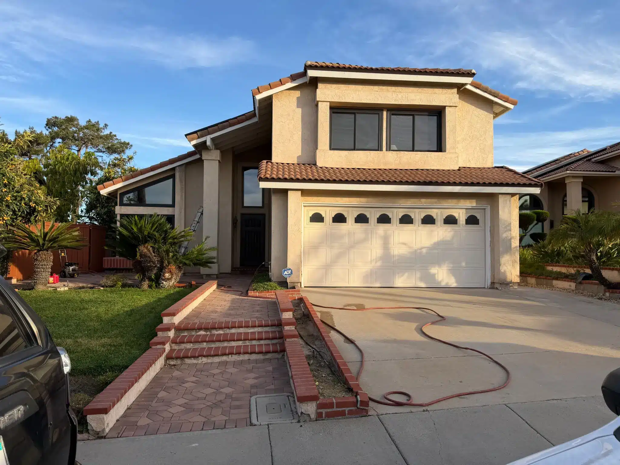 Complete Residential Exterior House Painting A two story residential house with beige stucco walls and a white garage door, ready for exterior painting.
