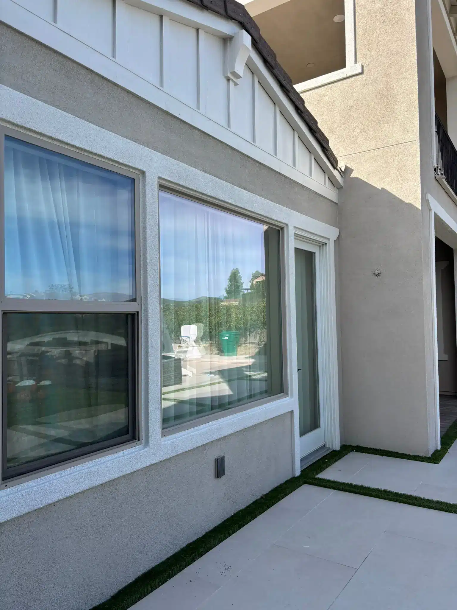 Modern Stucco House Exterior Painting and Trim A modern stucco house exterior with large windows and crisp white trim, showcasing professional painting.