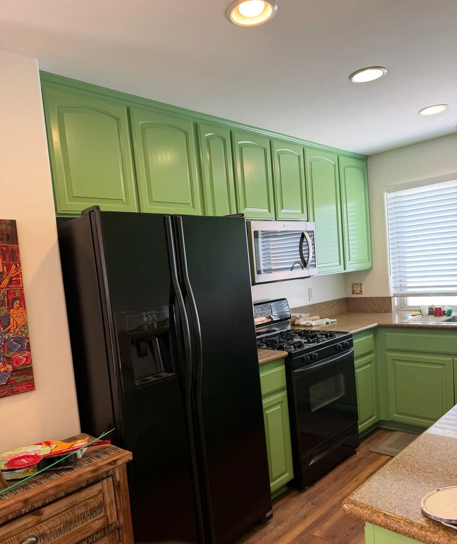 Complete Kitchen Cabinet Refinishing Service A modern kitchen featuring freshly painted green cabinets, a black refrigerator, and stove for a refreshed look.