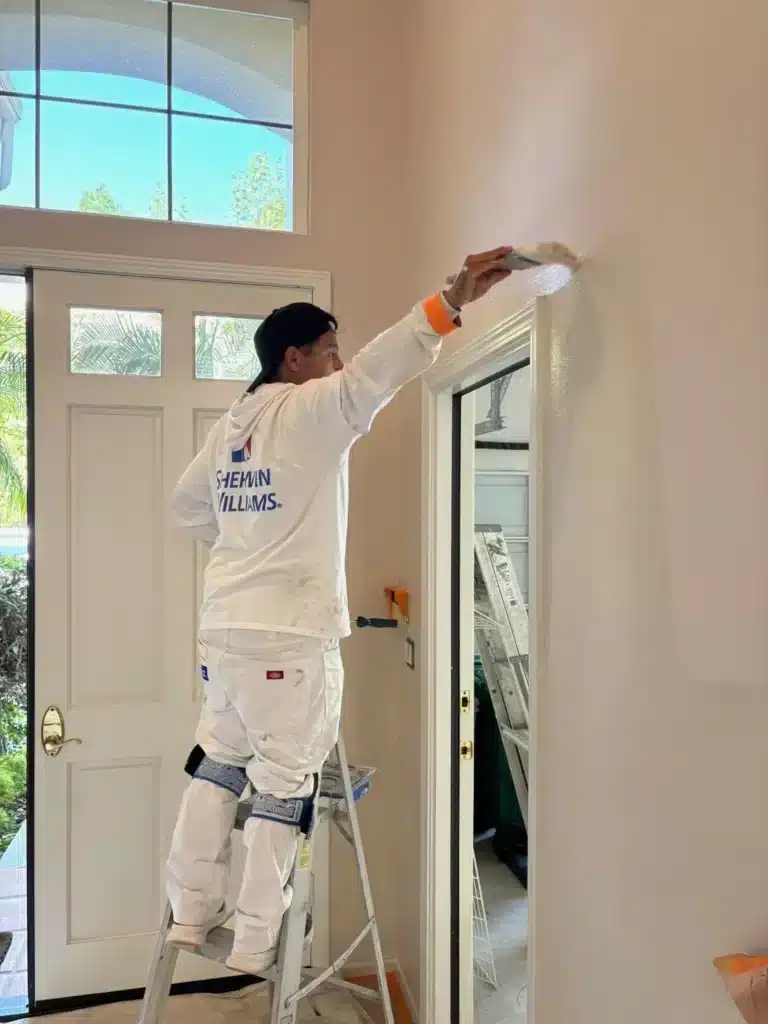 Professional Interior Wall Painting Service Professional painter working from a ladder on an interior wall